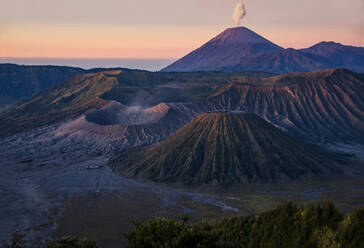 Atemberaubender Blick auf Mount Bromo aktiven somma Vulkan mit ausbrechenden weißen Rauch und Teil der Tengger Berge East Java Indonesien gegen orange Himmel - ADSF47493