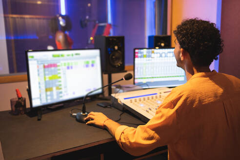 Faceless male audio engineer with mixing board and computer showing thumb up to anonymous singer while recording song in musical studio - ADSF47505