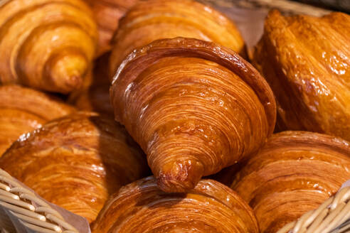 Closeup of delicious freshly baked crispy croissants placed in a wooden basket in a bakery kitchen - ADSF47570