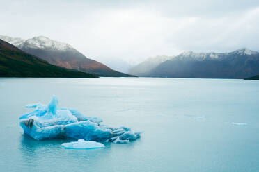 Picturesque view of mountain range with glacier peaks covered with snow with a huge lake against cloudy blue sky in winter at Perito Moreno Argentina - ADSF47597