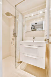 Sinks with mirrors and shower box with glass door in modern bathroom with white tiled walls - ADSF47685