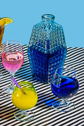 From above glass jar with blue color cocktail and varieties of colorful drinks Long Iceland Iced Tea wine Daiquiri lemon drop drink placed on striped surface in light - ADSF47732