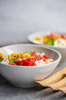 Healthy salads with assorted vegetables greens served in bowl with fork on a table with a blue background - ADSF47737