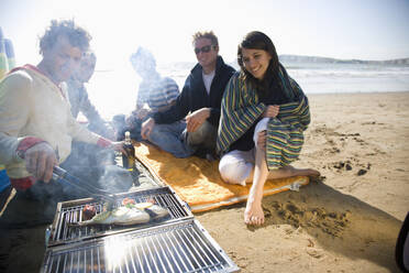 Friends sitting around a barbeque on the beach - FSIF06549