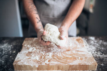 Male baker hands kneading dough on wooden table. Bread preparation. Homemade bakery - INGF12133