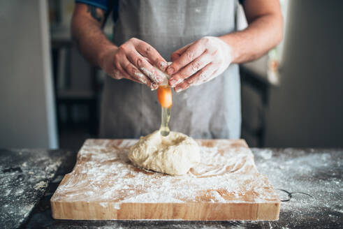 Chef hands mix the dough with egg. Bread preparation. Homemade bakery - INGF12136