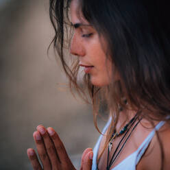 Young woman meditating with her eyes closed, practicing Yoga with hands in prayer position. - INGF12147