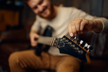 Young man guitarist tune guitar before playing. Music lesson creative hobby. Selective focus closeup. Young man guitarist tune guitar before playing - INGF12172