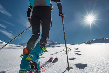 Skitourengeher klettert mit Robbenfellen einen verschneiten Hang hinauf - INGF12181