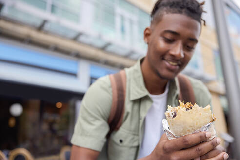 Young Man Eating Burrito At Outdoor Street Food Stall - INGF12184