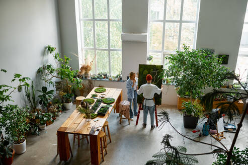 Floral design studio view with florists making decorations and arrangements view from afar. Floral design studio view with florists making decorations view from afar - INGF12187