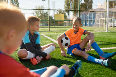 Teenage boys football team talking on soccer field resting after training or match. Teenage boys football team talking on soccer field - INGF12195