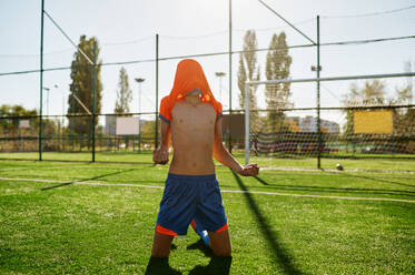 Emotional boy soccer player with t-shirt on head rejoicing goal or win showing yes gesture at stadium. Emotional boy soccer player with t-shirt on head rejoicing goal or win - INGF12196