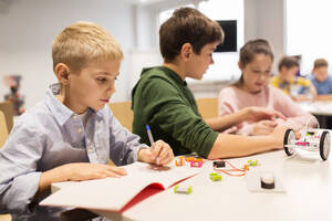 Education, children, technology, science and people concept - group of happy kids building robots at robotics school lesson. happy children building robots at robotics school - INGF12268