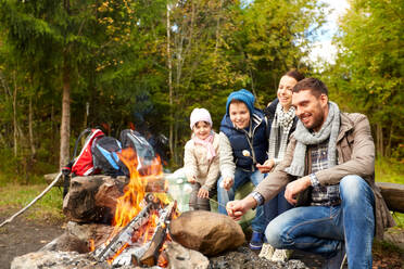 Camping, travel, tourism, hike and people concept - happy family roasting marshmallow over campfire. happy family roasting marshmallow over campfire - INGF12287
