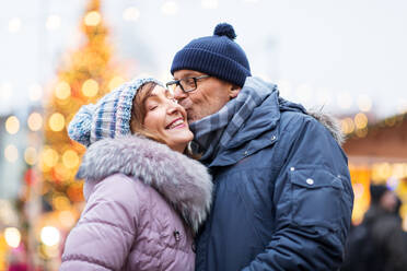 Love, winter holidays and people concept - happy senior couple kissing at christmas market. happy senior couple kissing at christmas market - INGF12297