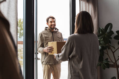 Versand, Transport und Menschen Konzept - Zusteller mit Paketkasten und Kunde zu Hause. Zusteller mit Paketkasten und Kunde zu Hause - INGF12322