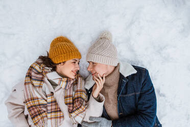 People, love and leisure concept - happy smiling couple lying on snow in winter. happy smiling couple lying on snow in winter - INGF12326