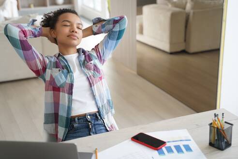 Handsome hispanic girl is studying remote at home. Teenage girl has leaned back, closed her eyes and dreaming. Lazy student distracting at online virtual lesson. Schoolgirl has rest from study.. Lazy student, hispanic girl is studying remote. Teenage girl has leaned back and closed her eyes. - INGF12357