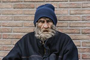 Bearded homeless man front wall - INGF12368