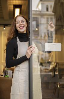 Young woman holding shop sign 6 - INGF12381