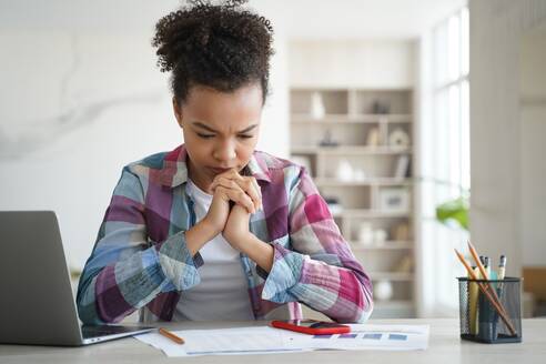 Schoolgirl has concentration problem. Overworked african american girl is studying remote at home. Teenage girl is sitting at workplace exhausted from homework. Distance learning on quarantine.. Schoolgirl has concentration problem. Overworked african american girl is studying remote at home. - INGF12392