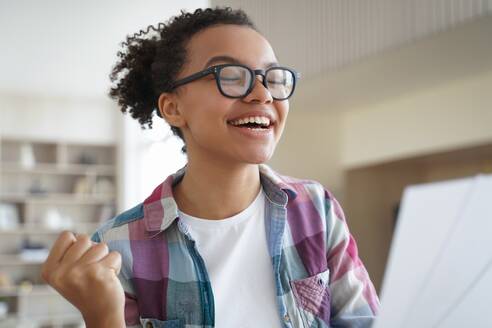 Excited african american teen girl in glasses feels happiness, received good news. Biracial female student celebrate victory, enjoy success, personal achievement, got student scholarship.. Excited african american teen girl in glasses celebrate victory, enjoy success, personal achievement - INGF12395