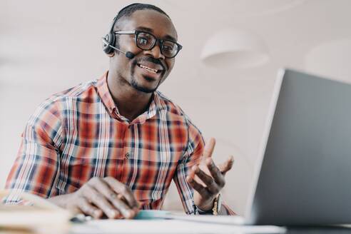 Friendly manager of client support service. African american man in headset receives calls. Online shop assistant is working from home. Teacher has remote lesson. Student gets distant education.. Friendly manager of client support service. African american man in headset receives calls. - INGF12405