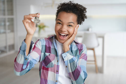 Excited young african american teen girl tenant showing keys of first new house. Happy biracial female delighted with buying or renting apartment holds home key. Relocation, real estate rent service. Excited african american teen girl tenant showing keys of first new house. Real estate rent service - INGF12438