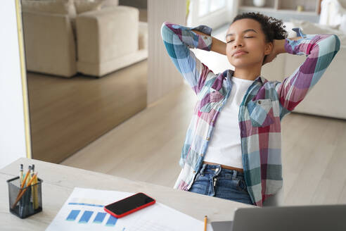 Handsome hispanic girl is studying remote at home. Teenage girl has leaned back, closed her eyes and dreaming. Lazy student distracting at online virtual lesson. Schoolgirl has rest from study.. Lazy student, hispanic girl is studying remote. Teenage girl has leaned back and closed her eyes. - INGF12441