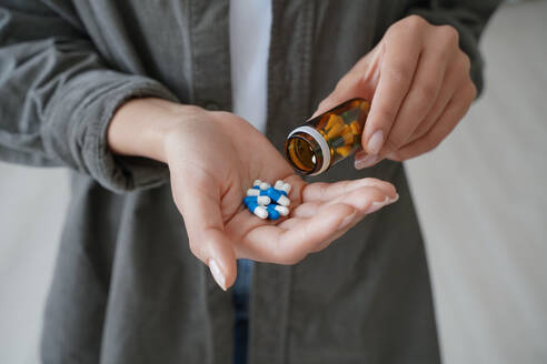 Drug addiction. Hand of african american girl holding medicine drugs and flacon. Teenage spanish girl or young woman taking vitamins or painkillers. Medications and pharmaceutical treatment.. Drug addiction. Hand of african american girl or young woman holding medicine drugs and and flacon. - INGF12445