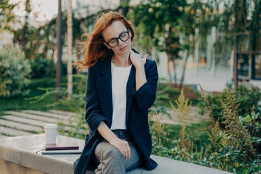 Young tired businesswoman massaging neck, feeling pain in body muscles because of bad posture at work, sitting in park after long working day in office, overworked female suffering from backache,. Young tired woman massaging neck, feeling pain in body muscles because of bad posture at work - INGF12490