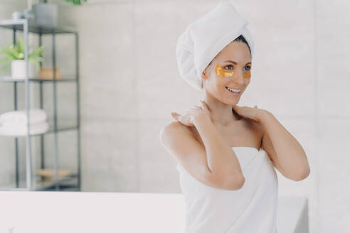 Frau mit Augenklappen genießt die Hautpflege im Badezimmer nach der Dusche. - INGF12551