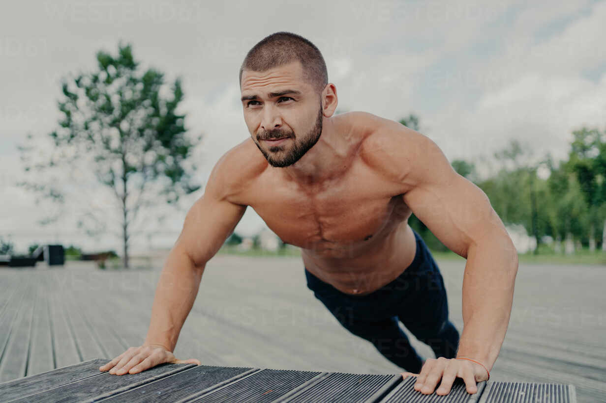 Foto de Naked shirtless fitness man doing push ups - muscular abs do Stock