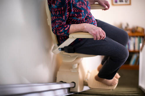 Detail Of Senior Woman Sitting On Stair Lift At Home To Help Mobility - INGF12647