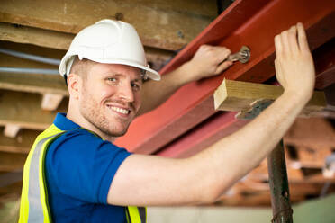 Construction Worker Fitting Steel Support Beam Into Renovated House Ceiling - INGF12650