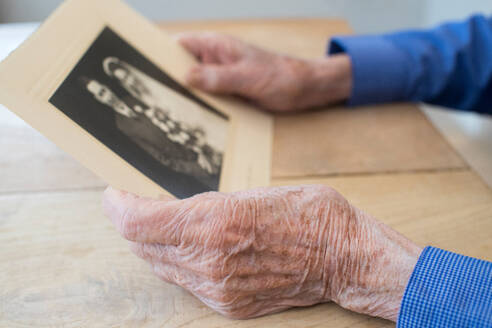 Close Up Of Senior Man Holding Wedding Photograph - INGF12659