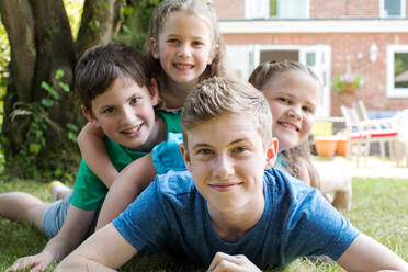 Portrait Of Four Brothers And Sisters Lying In Garden At Home - INGF12664