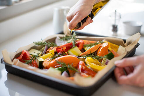 Close Up Of Seasoning Tray Of Vegetables For Roasting With Olive Oil Ready For Vegan Meal - INGF12666