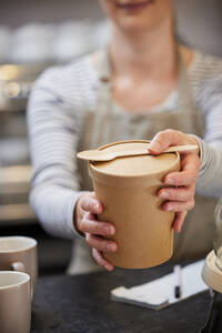 Close Up Of Female Worker in Cafe Serving Meal In Sustainable Recyclable Packaging With Wooden Spoon - INGF12677