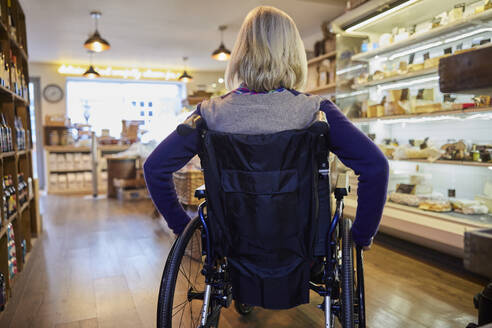 Rear View Of Woman In Wheelchair Shopping For Food In Delicatessen - INGF12697