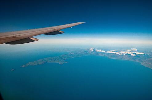 An aerial view across the northern end of Cardigan Bay towards Anglesey and Snowdonia (which is covered in cloud) - view includes wingtip of aircraft. Aerial view of North Cardigan Bay, Wales - INGF12740