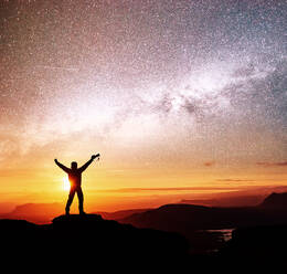 Silhouette of woman is standing on top of mountain and pointing to The milky way before sunrise and enjoying with colorful night sky.. Silhouette of woman is standing on top of mountain and pointing to The milky way before sunrise and enjoying with colorful night sky - INGF12743