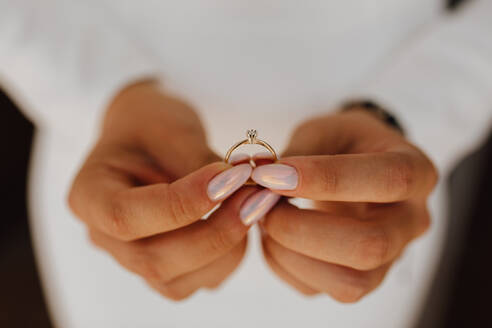 Bride is holding engagement ring with diamond in hands with beautiful manicure, front view, wedding day - INGF12750