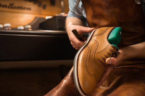 Cropped image of young shoemaker in workshop making shoes.. Shoemaker in workshop making shoes. - INGF12764