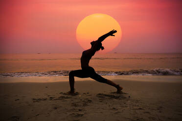 Silhouette young woman practicing yoga on the beach at sunrise - INGF12765