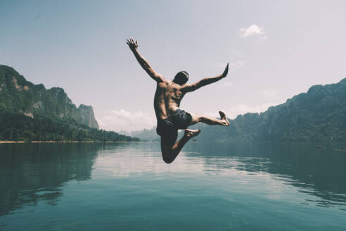 Man jumping with joy by a lake - INGF12770