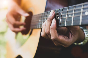 Close up of guitarist hand playing guitar. Musical and instrument concept. Outdoors and Leisure theme. Selective focus on left hand. - INGF12773