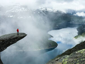 Man sits at the end of Trolltunga before the mountains - INGF12816