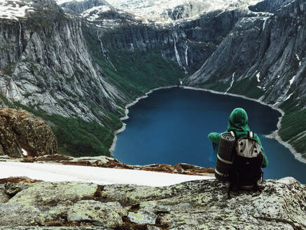 Man sits at the end of Trolltunga before the mountains - INGF12818